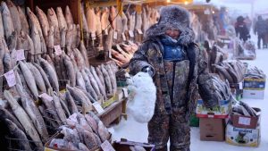 A-local-woman-holds-an-arctic-hare-on-sale-along-with-her-stock-of-frozen-fish-in-the-central-market-of-Yakutsk.-Welcome-to-The-Coldest-Place-Inhabited-By-Humans-on-Earth