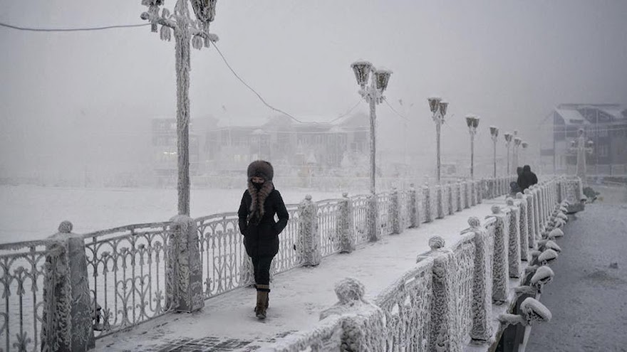A-woman-walks-over-an-ice-encrusted-bridge-in-Yakutsk.-Oymyakon-lies-a-two-day-drive-from-the-city-of-Yakutsk-the-regional-capital-Welcome-to-The-Coldest-Place-Inhabited-By-Humans-on-Earth
