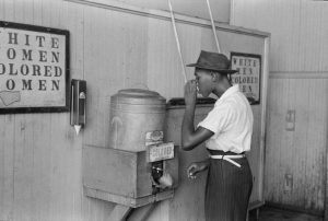 A black man drinking from the Colored water cooler in Oklahoma City in July, 1939